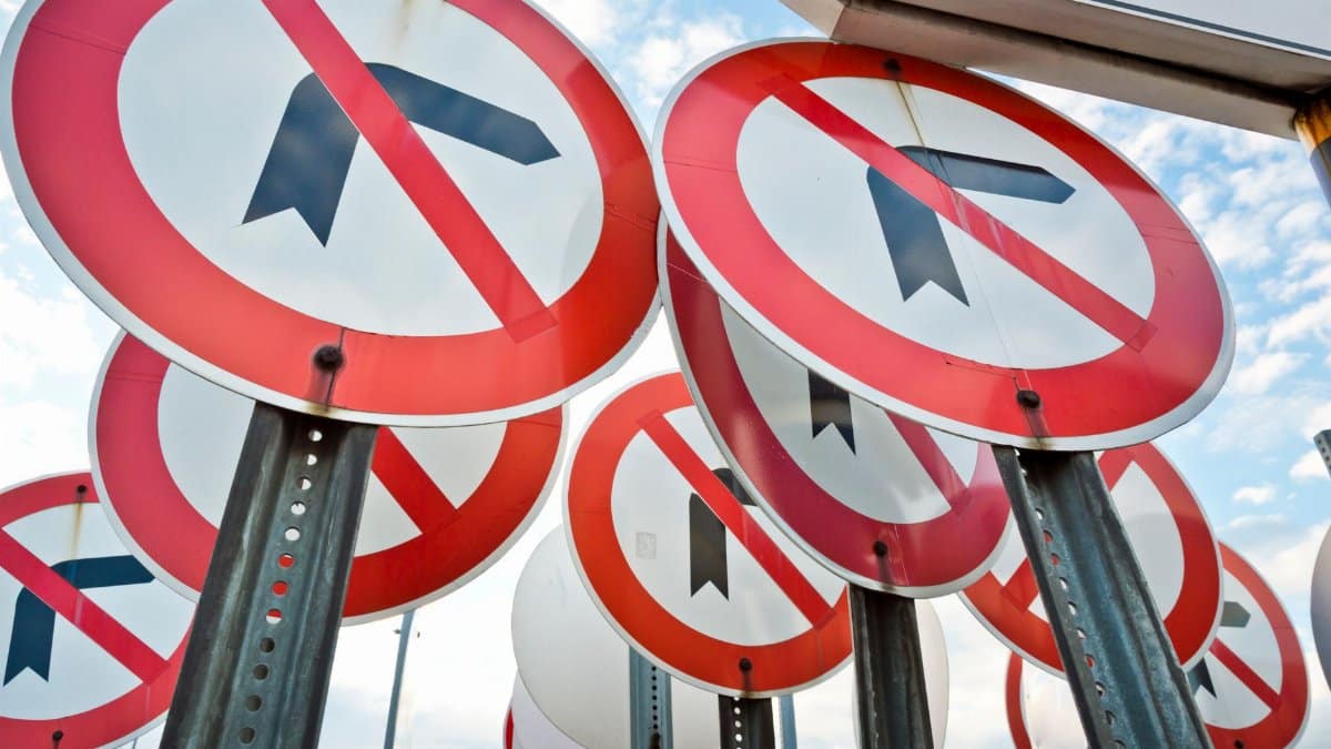 Multiple no left turn traffic signs displayed together under a blue sky.