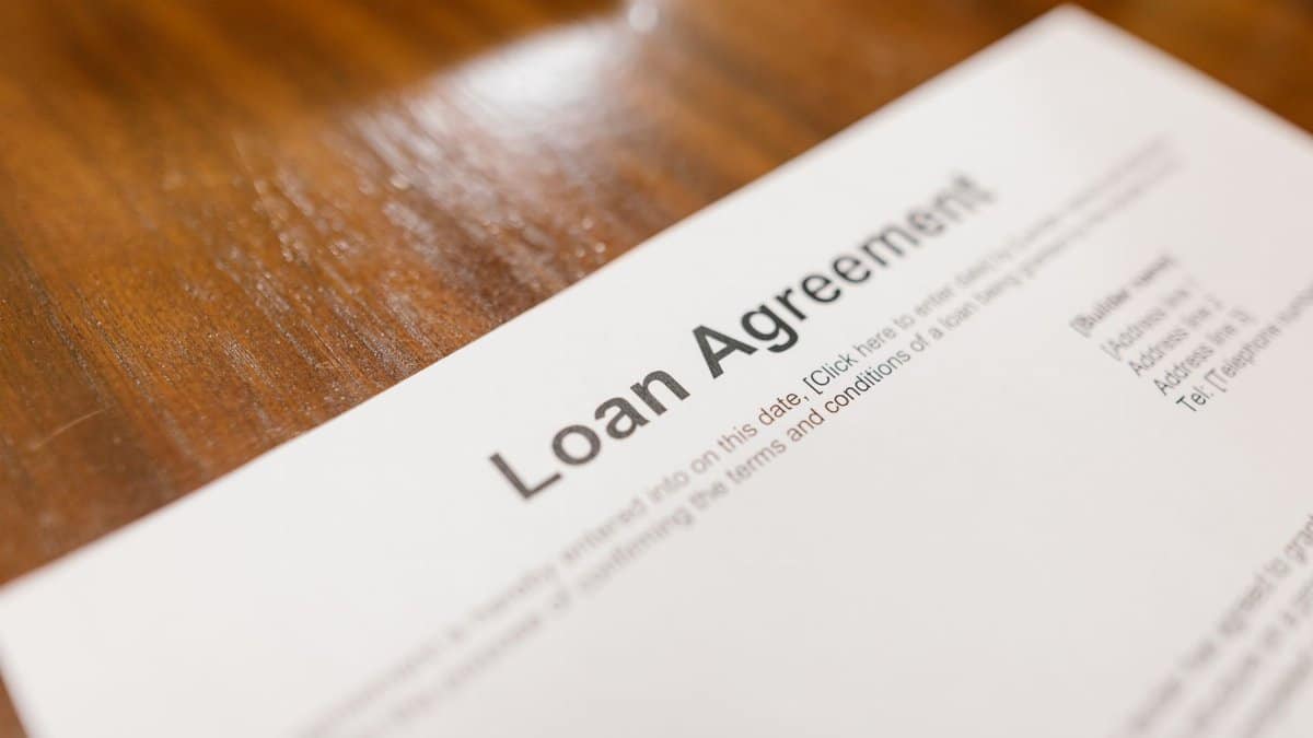Detailed loan agreement document close-up on a wooden table representing legal and financial concepts.