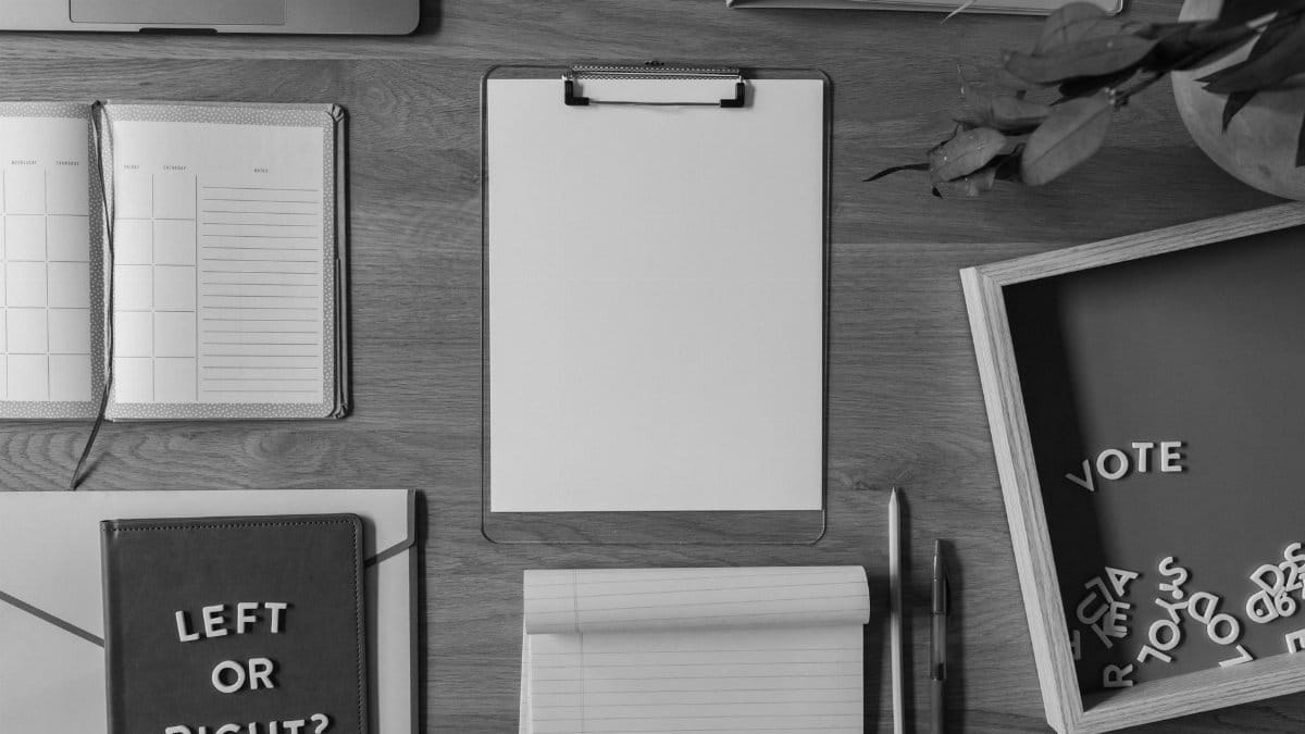 Top view of a desk with voting-themed items, including a notepad with 'Left or Right?' and scattered letters spelling 'Vote'.