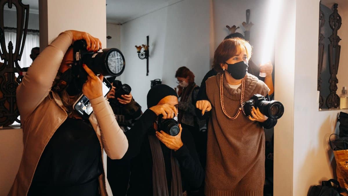 Photographers with cameras and lighting equipment during an indoor photoshoot.