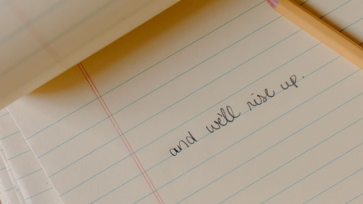Close-up of a motivational phrase written on a notepad with a pencil.
