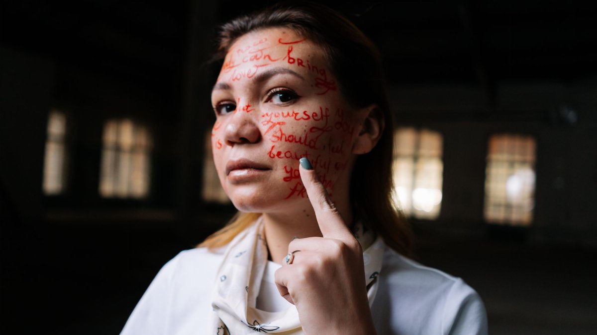 A woman with words written on her face poses in an artistic expression of activism and self-identity.