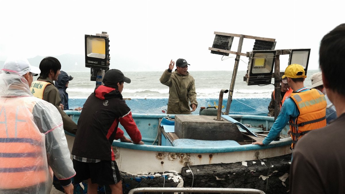 Fishermen gather around a boat preparing for a sea expedition, teamwork in action.