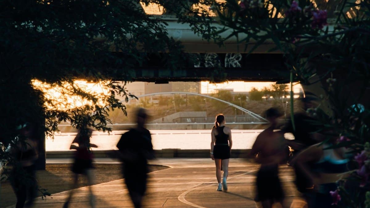 People jogging along Tempe Town Lake during a vibrant sunset, showcasing fitness and outdoor activity.