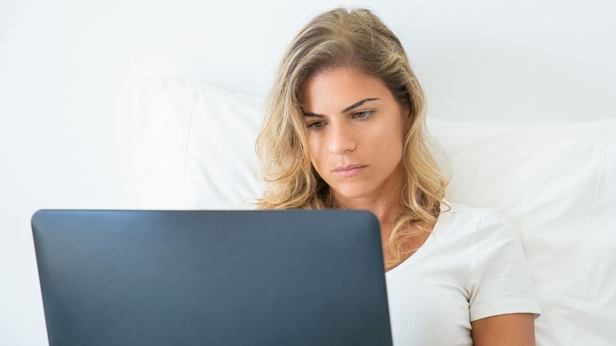 A woman attentively working on her laptop while sitting comfortably at home, showcasing remote work lifestyle.