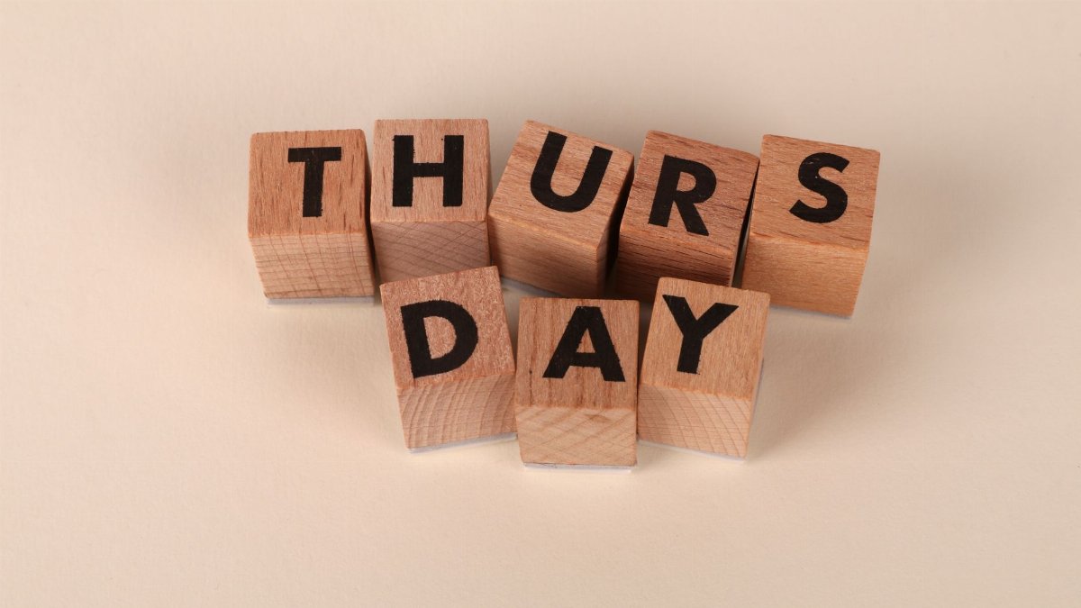 Wooden letter blocks arrange to spell 'Thursday' on a plain background, ideal for week or calendar themes.
