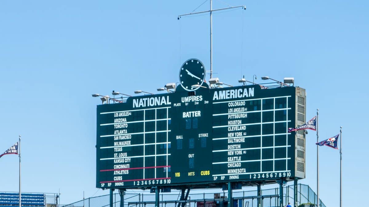 Historic Wrigley Field scoreboard showcasing teams under a clear blue sky in Chicago.