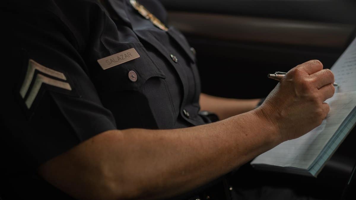 Close-up of a police officer writing in a notebook while sitting in a car, focused detail.