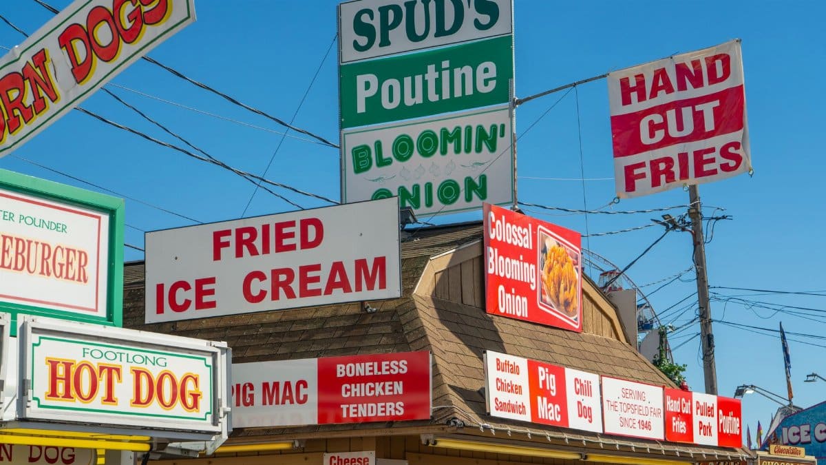 Bright food stand signs at the Topsfield Fair in Massachusetts, offering a variety of snacks.