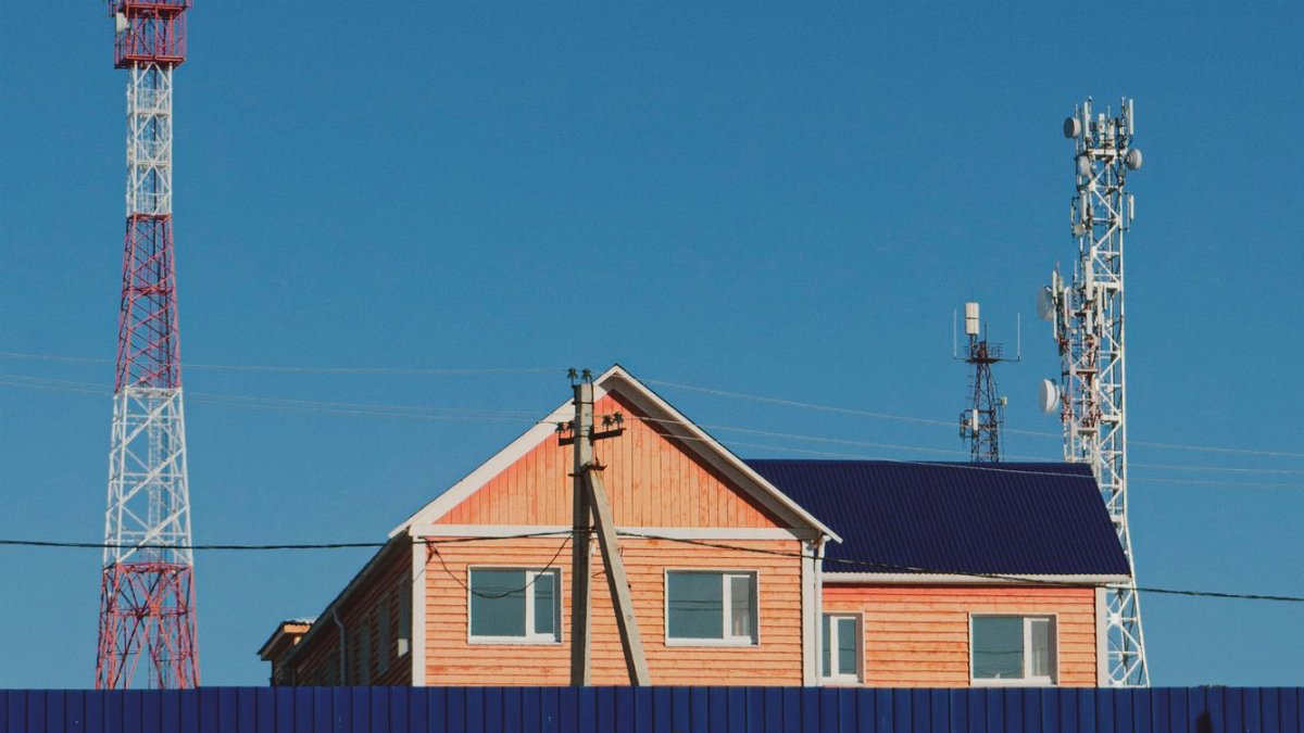 A contemporary house with communication towers under a clear blue sky, showcasing urban infrastructure.