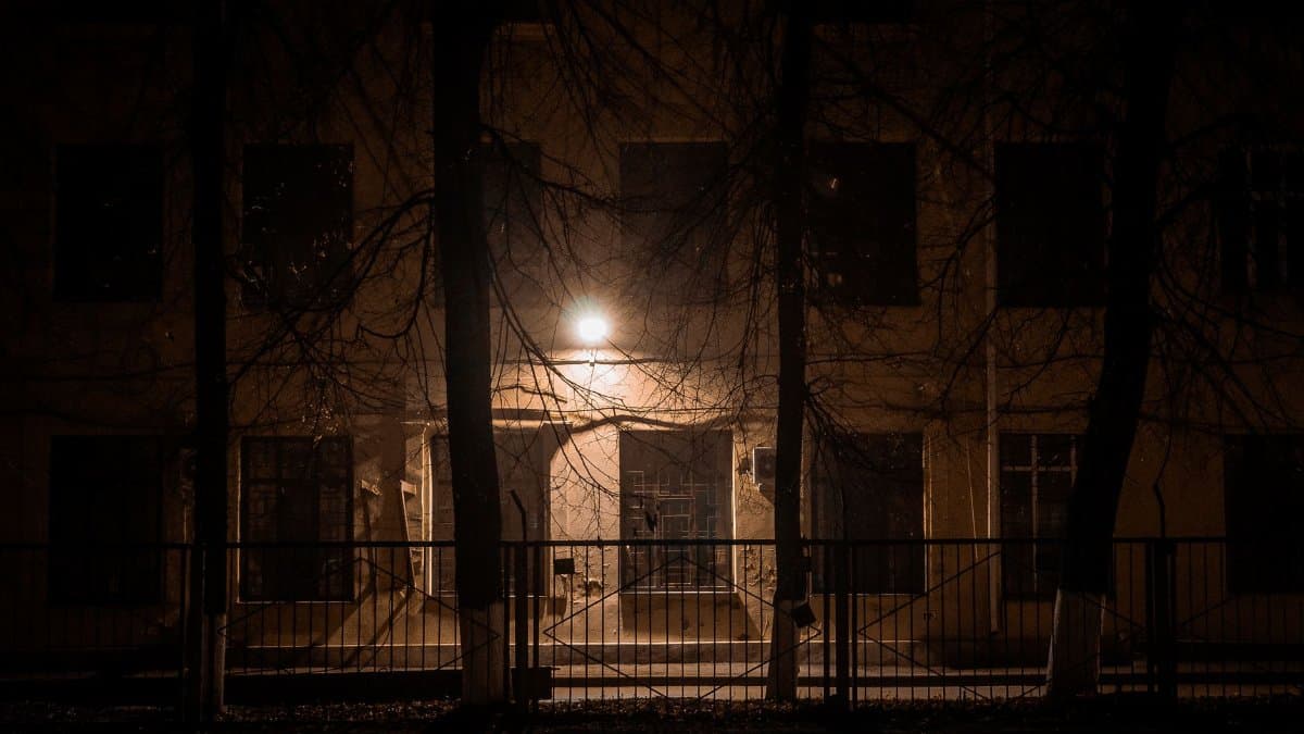 Mysterious night scene of an urban building with dim lights and barren trees.