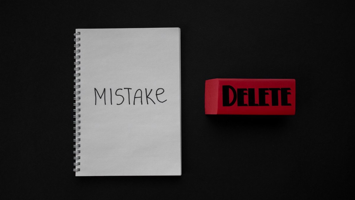Notebook labeled 'Mistake' next to a red delete eraser on a dark background.