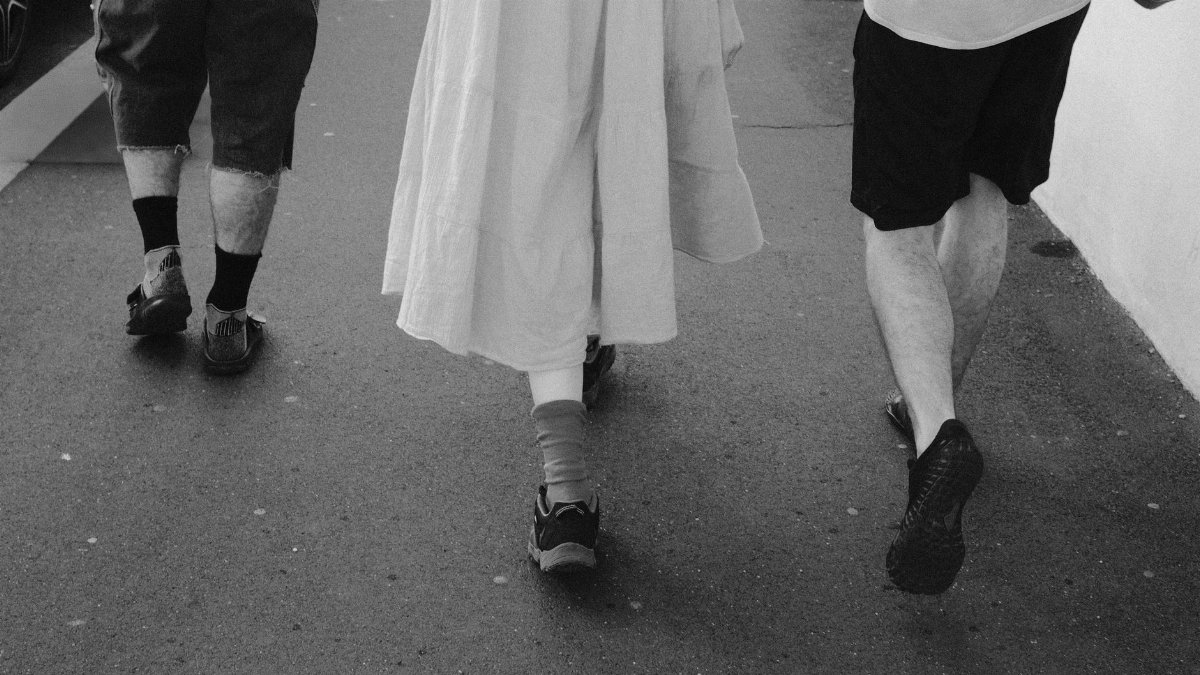 Three people walk down a city street in monochrome tone.
