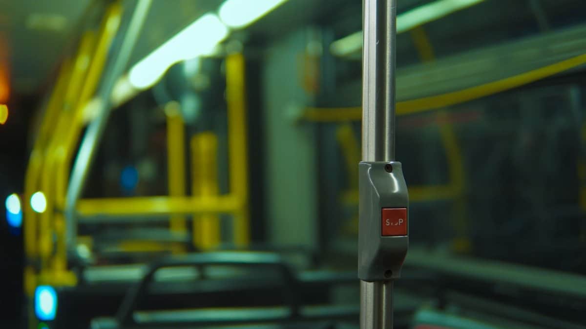 Close-up of a stop button inside a city bus with dim lighting, highlighting public transit details.