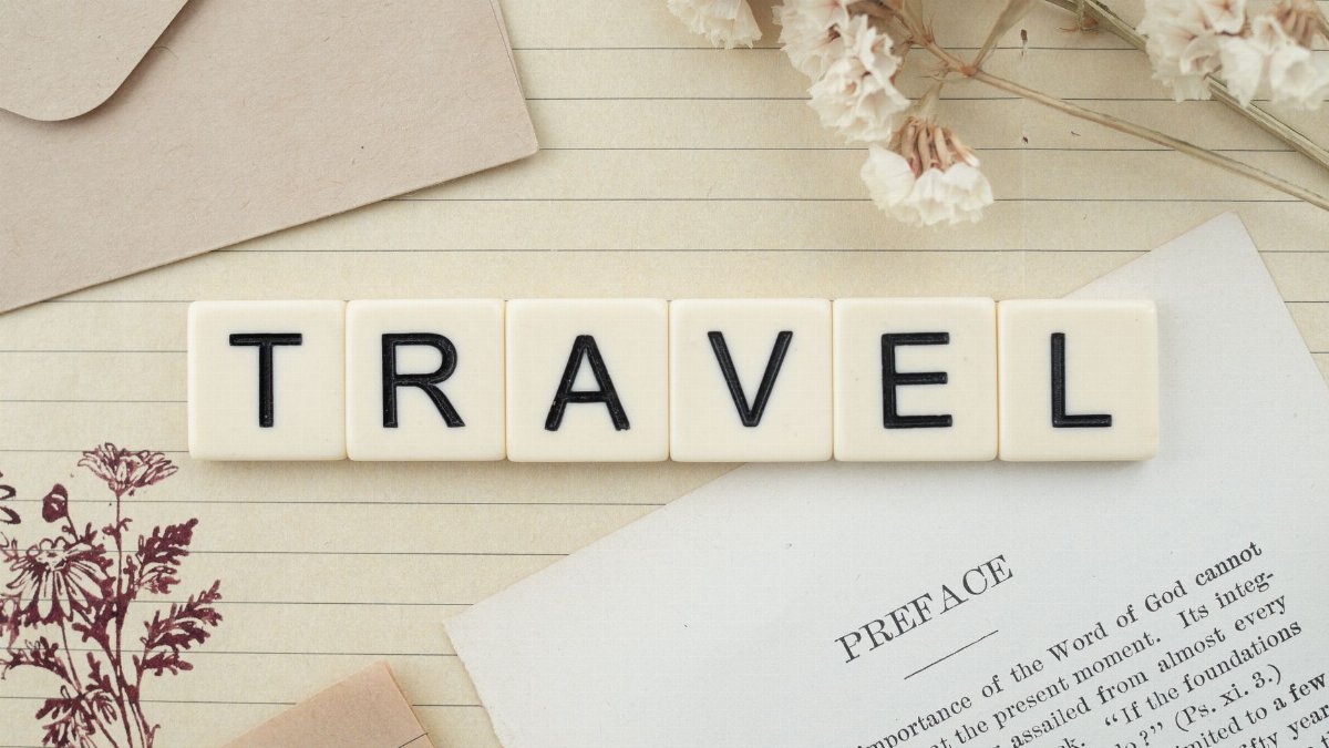Travel-themed flat lay with Scrabble tiles, dried flowers, and stationery creating a vintage vibe.