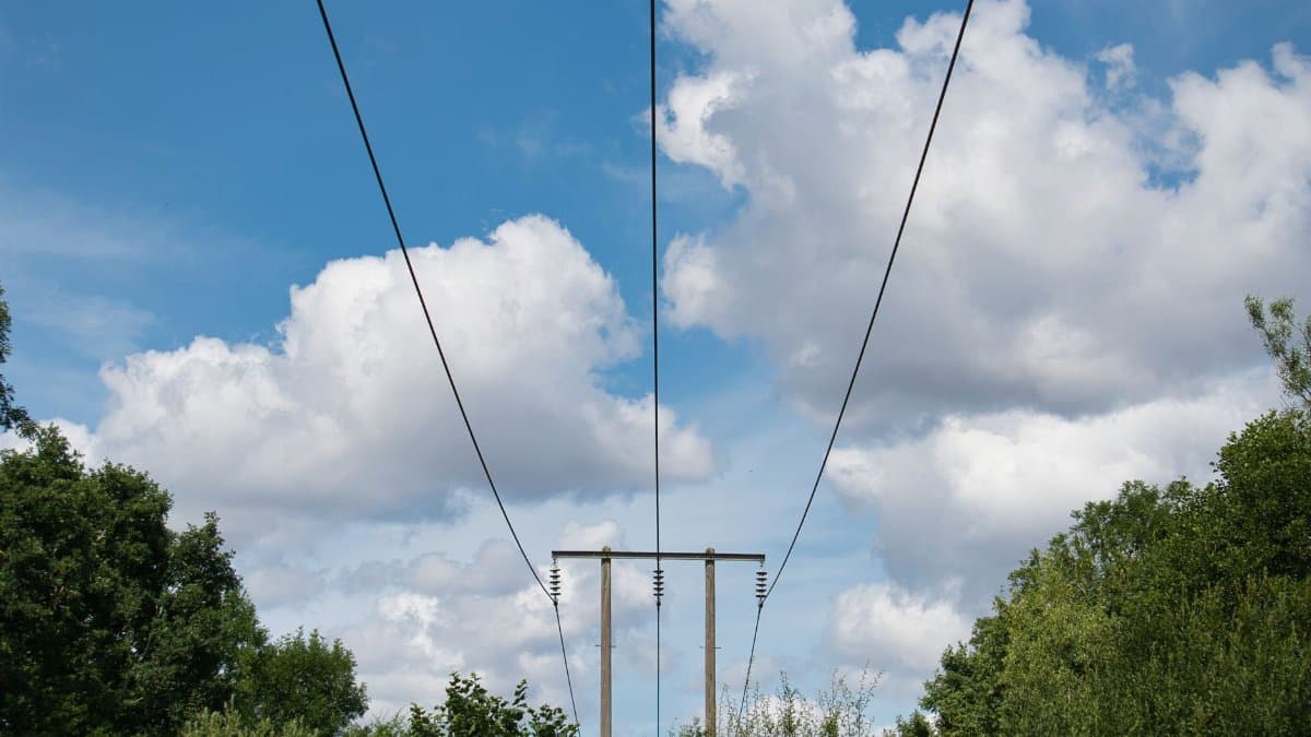 Scenic view of power lines stretching across a bright blue sky with fluffy clouds in the United Kingdom.