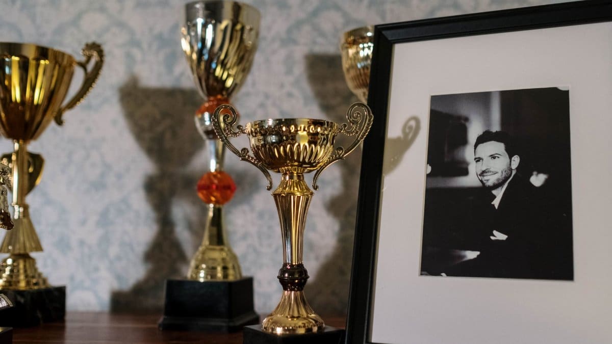 A collection of trophies with a framed black and white portrait on a shelf.