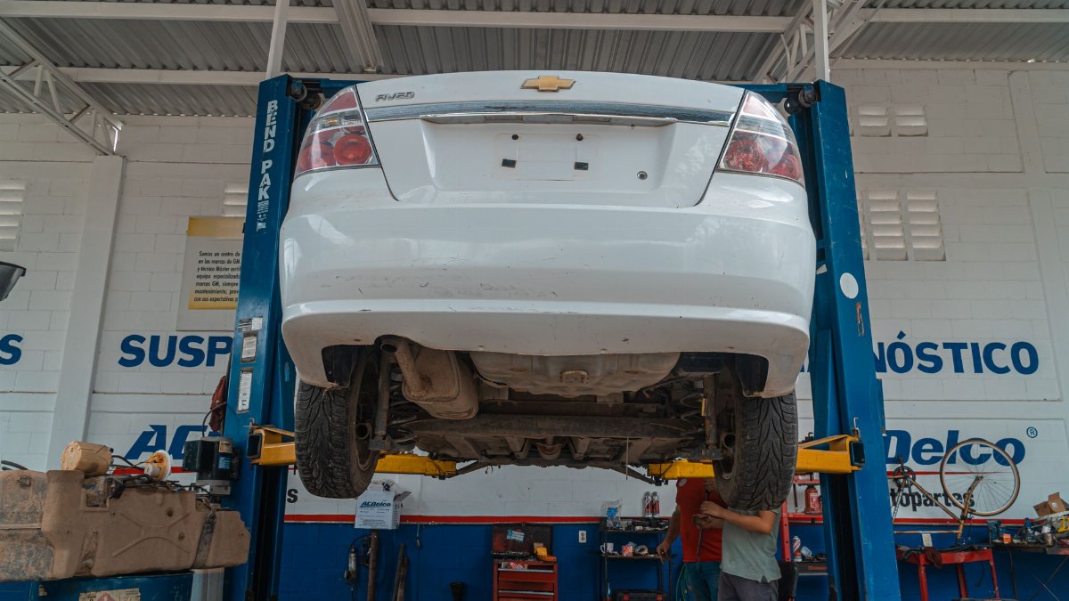 A white Chevrolet car is lifted for maintenance in an automotive repair shop.