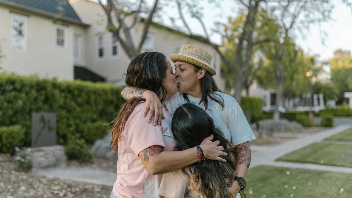 Loving lesbian parents with daughter sharing a heartfelt moment in the yard.
