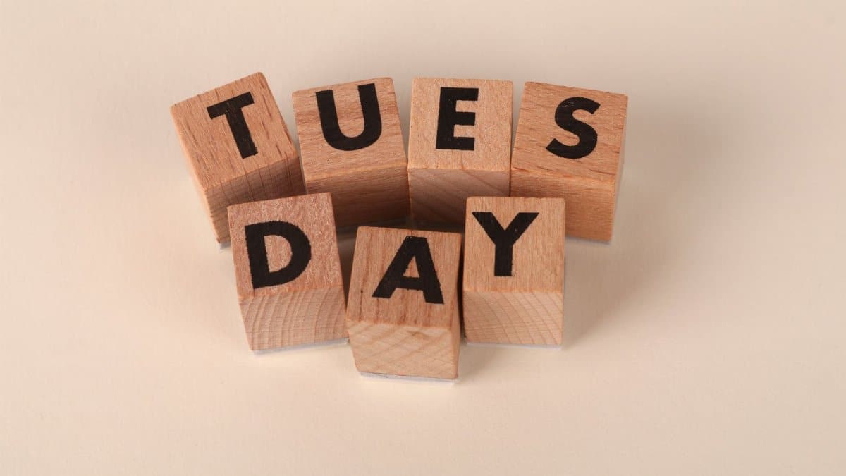 Wooden blocks arranged to spell 'Tuesday' on a beige background.