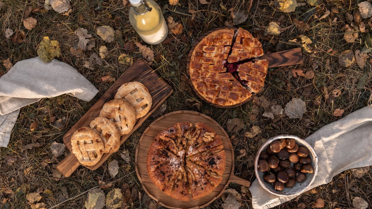 Flat lay of pies and chestnuts on autumn leaves, perfect for cozy food moments.