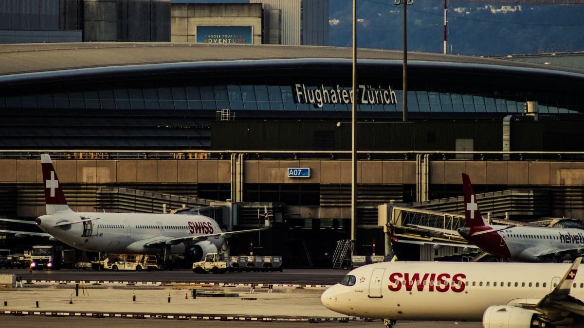 Swiss Airlines planes parked at Zurich Airport with clear view of terminal building.