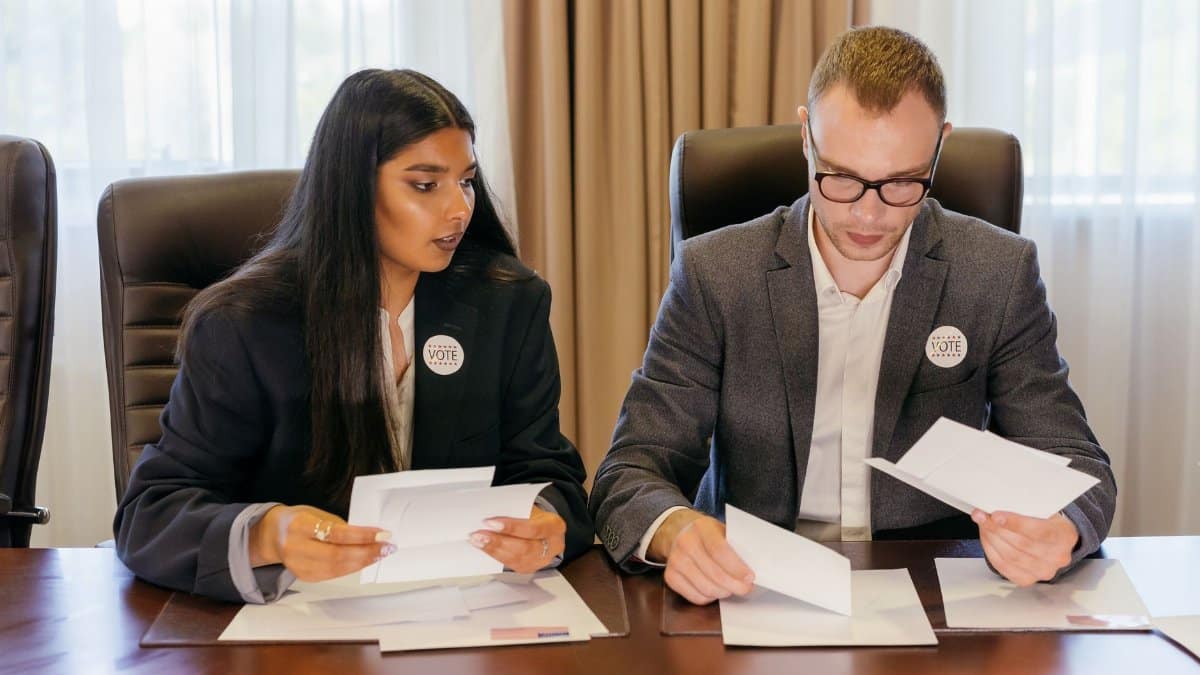 Two professionals in a meeting reviewing documents at a conference table.