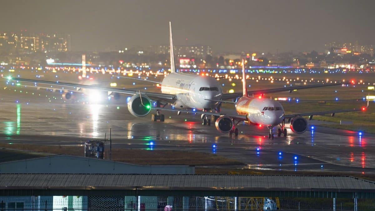 A captivating view of airplanes on a lit runway at night with city lights in the background.