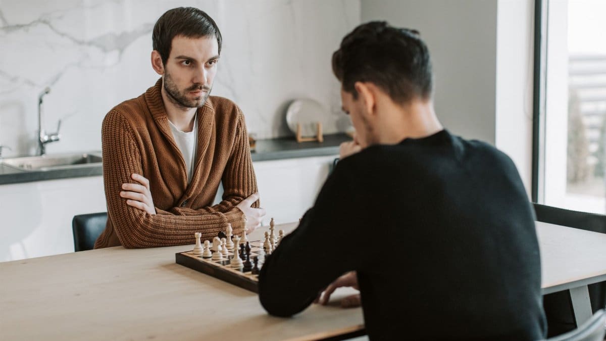 Two men play an intense chess match indoors, highlighting focus and strategy.