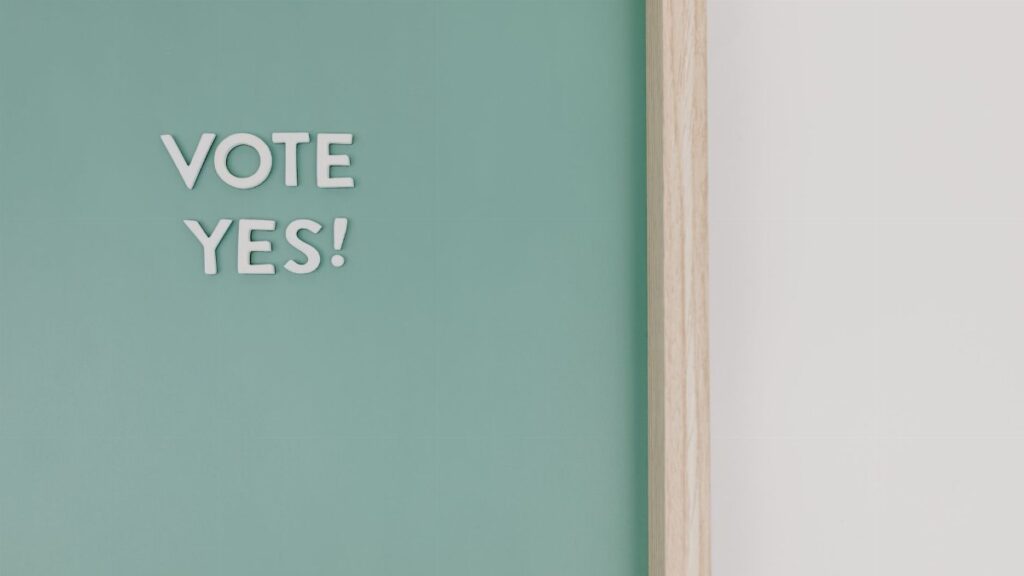 Close-up of a chalkboard with 'Vote Yes!' text, offering copy space.