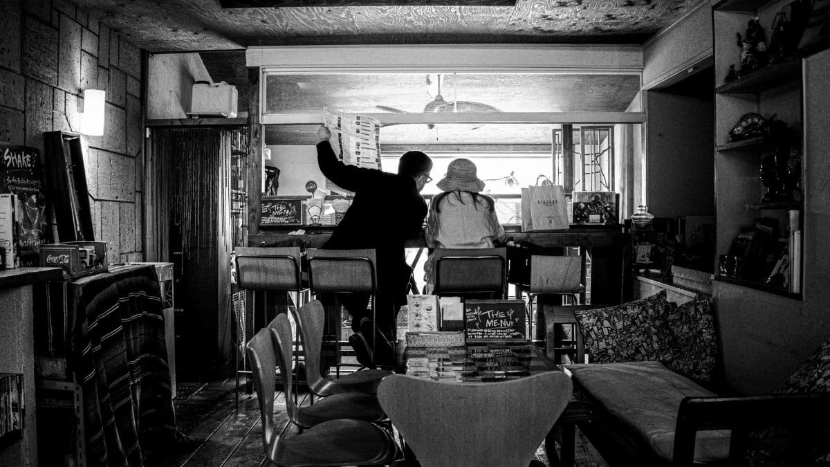 Intimate black and white photo capturing two people in a cozy cafe setting, with vintage decor.