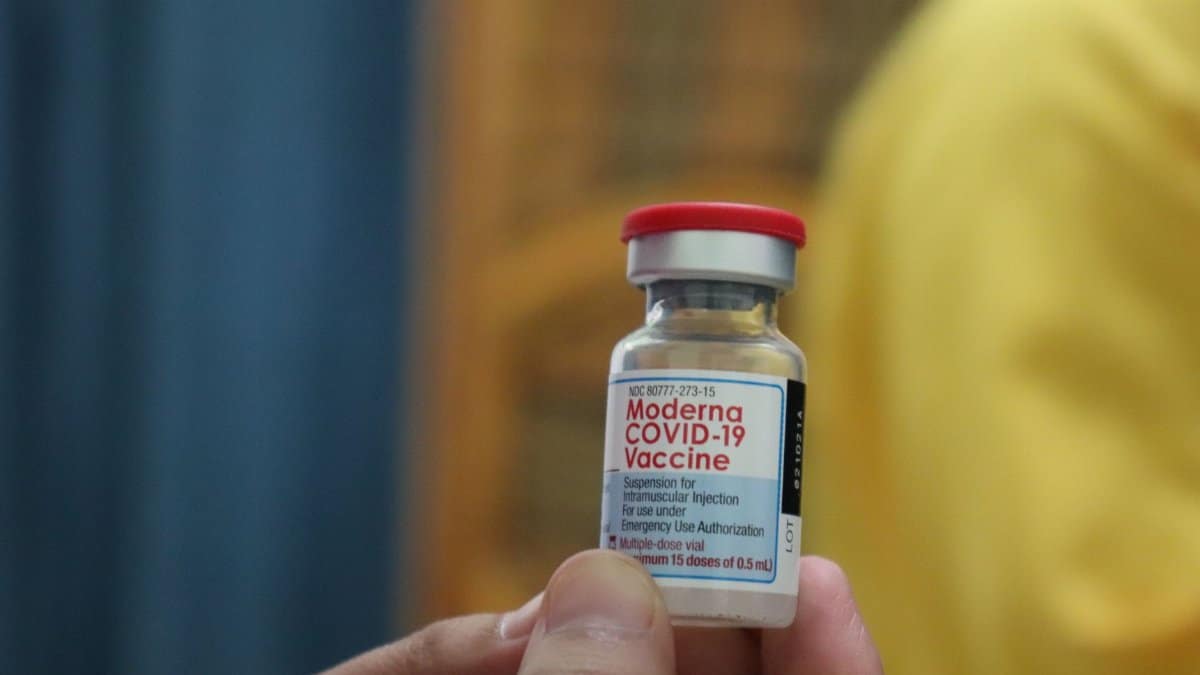 Detailed view of a Moderna COVID-19 vaccine vial held in hand, highlighting immunization efforts.