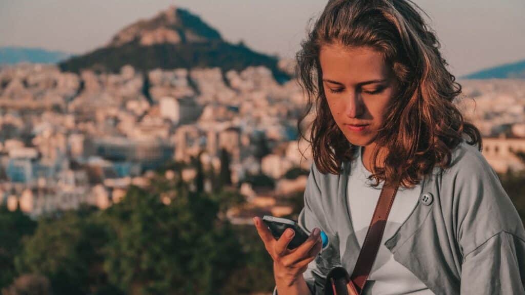 Young woman using a smartphone with Athens, Greece as the backdrop.