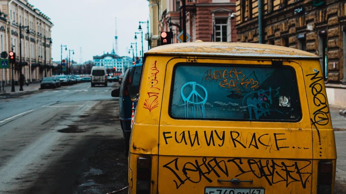 Yellow van with graffiti parked on urban street, showcasing vibrant city life in St. Petersburg.