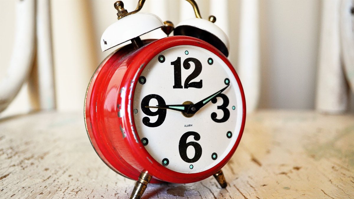 Close-up of vintage red alarm clock on rustic wood surface, indoors.