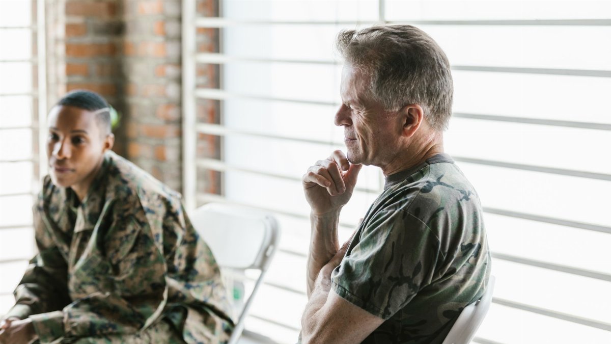 Two military veterans participate in a supportive therapy session, focusing on mental health and recovery.