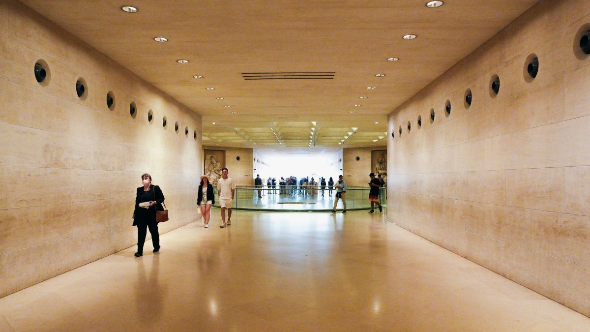 A well-lit museum corridor with visitors, featuring modern architecture.