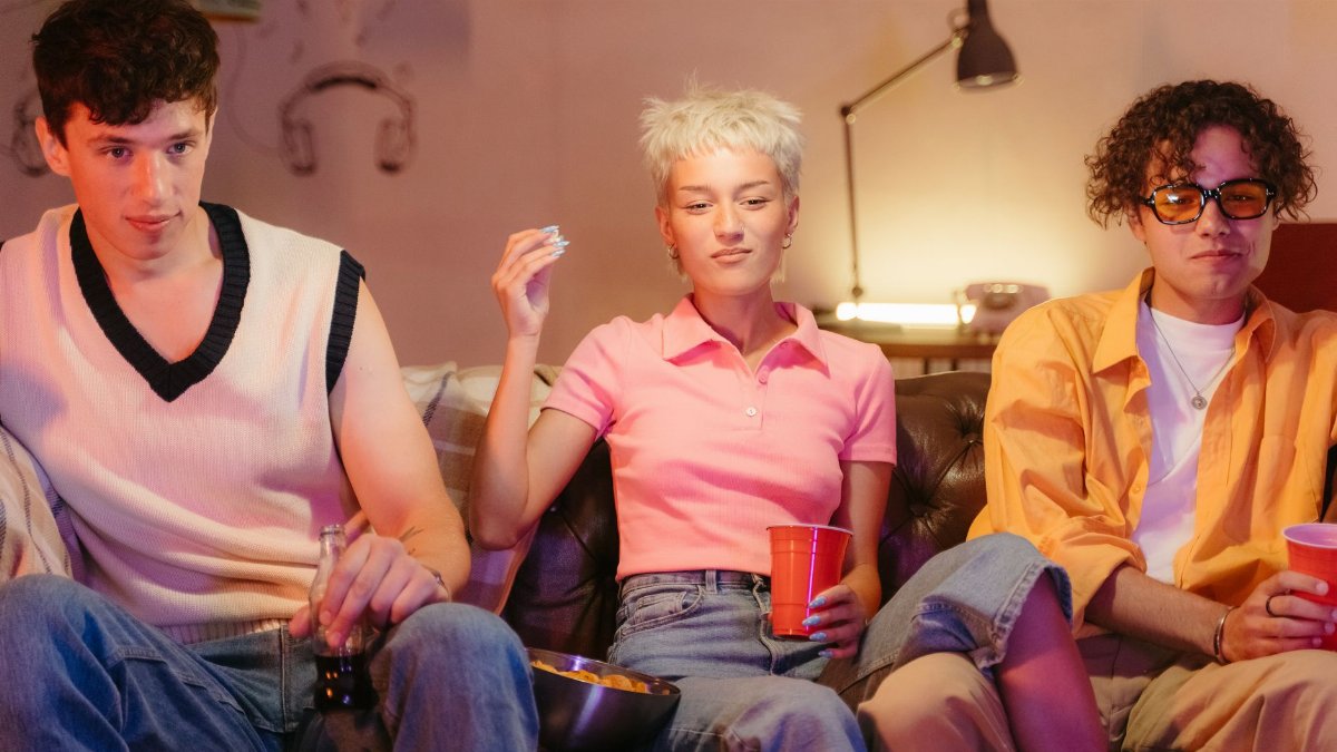 Three teenagers having fun indoors during a nostalgic movie night with snacks.