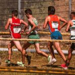 A team of male athletes competing in an outdoor cross-country race on a sunny day.