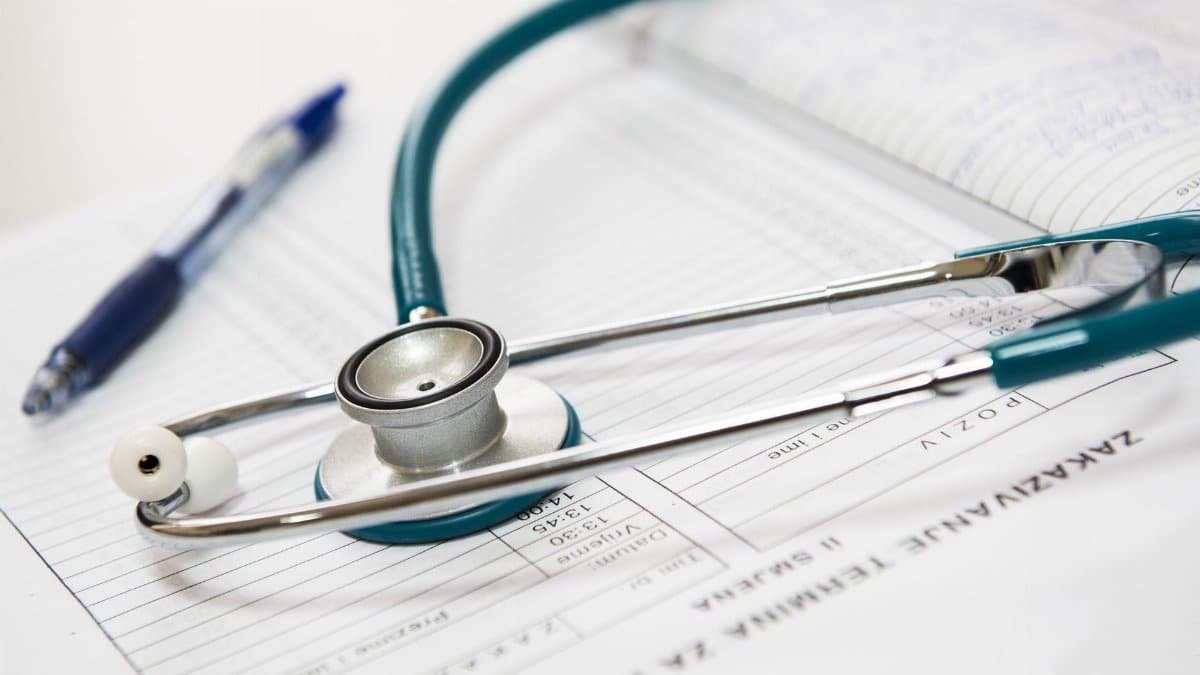 A stethoscope and pen resting on a medical report in a healthcare setting.