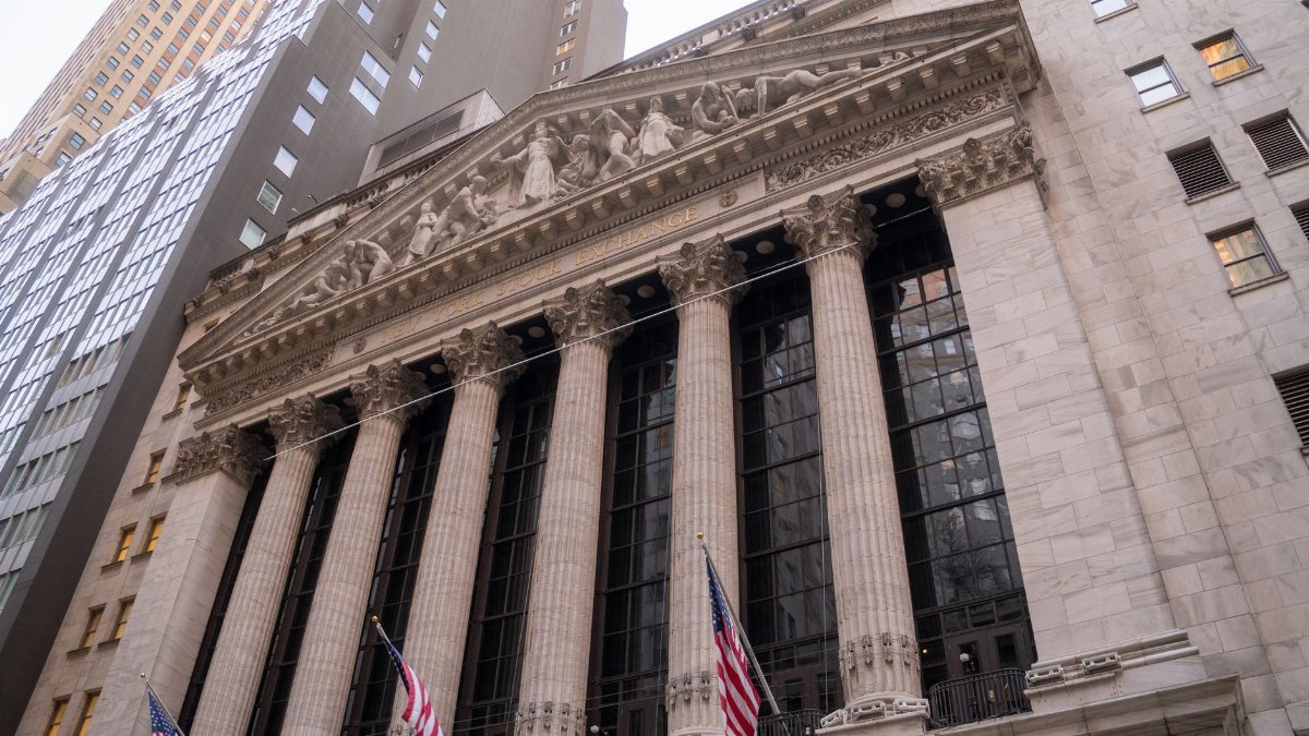 Close-up view of the iconic New York Stock Exchange building with American flags, located in Wall Street, NYC.