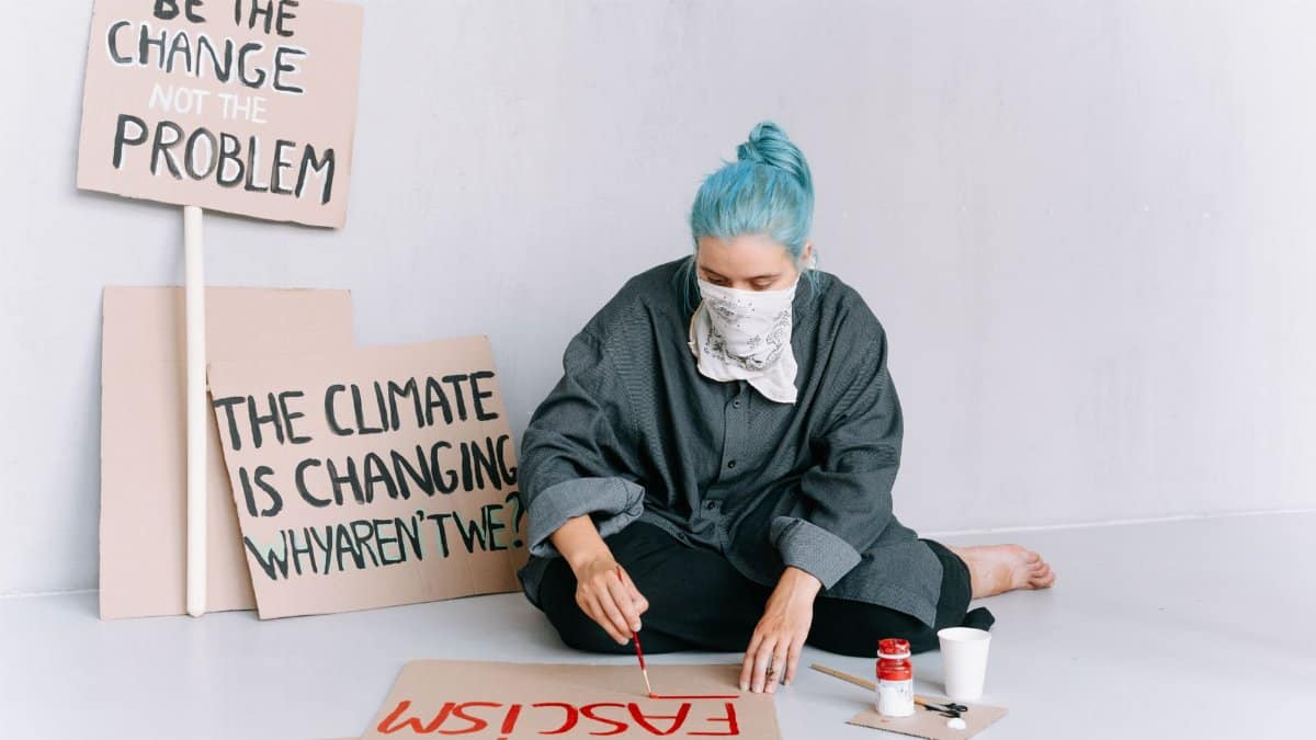 A woman paints protest signs with messages on climate change and social activism.