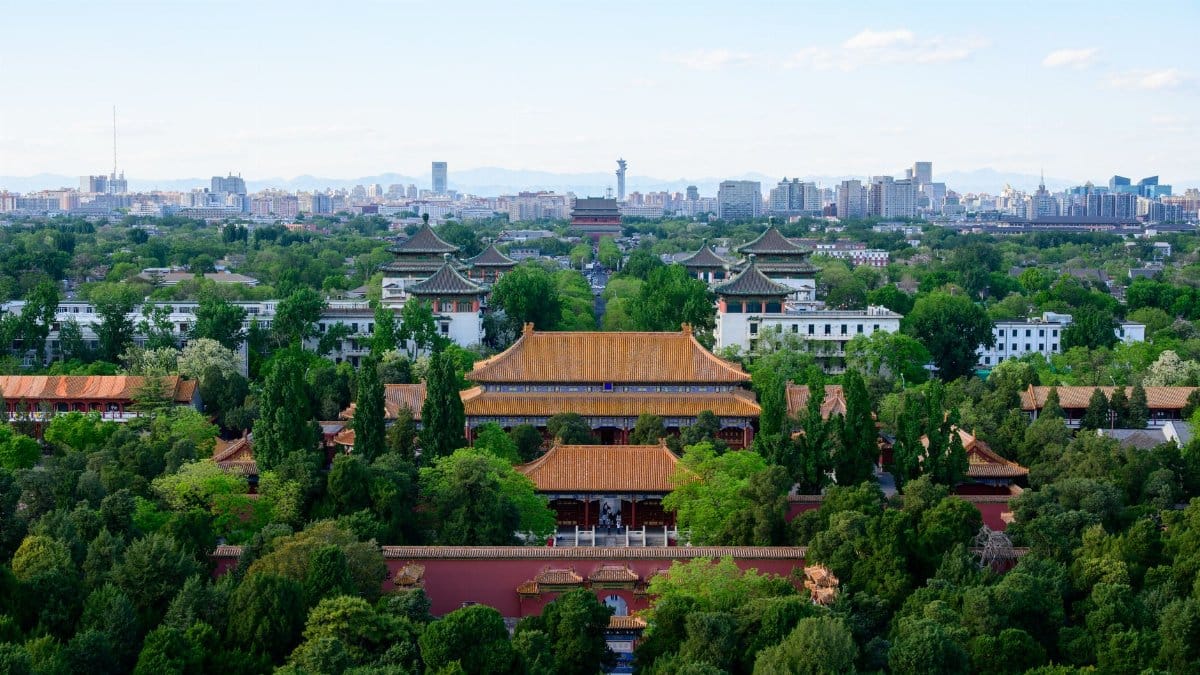 A stunning aerial view of ancient Chinese architecture with Beijing's city skyline in the background.