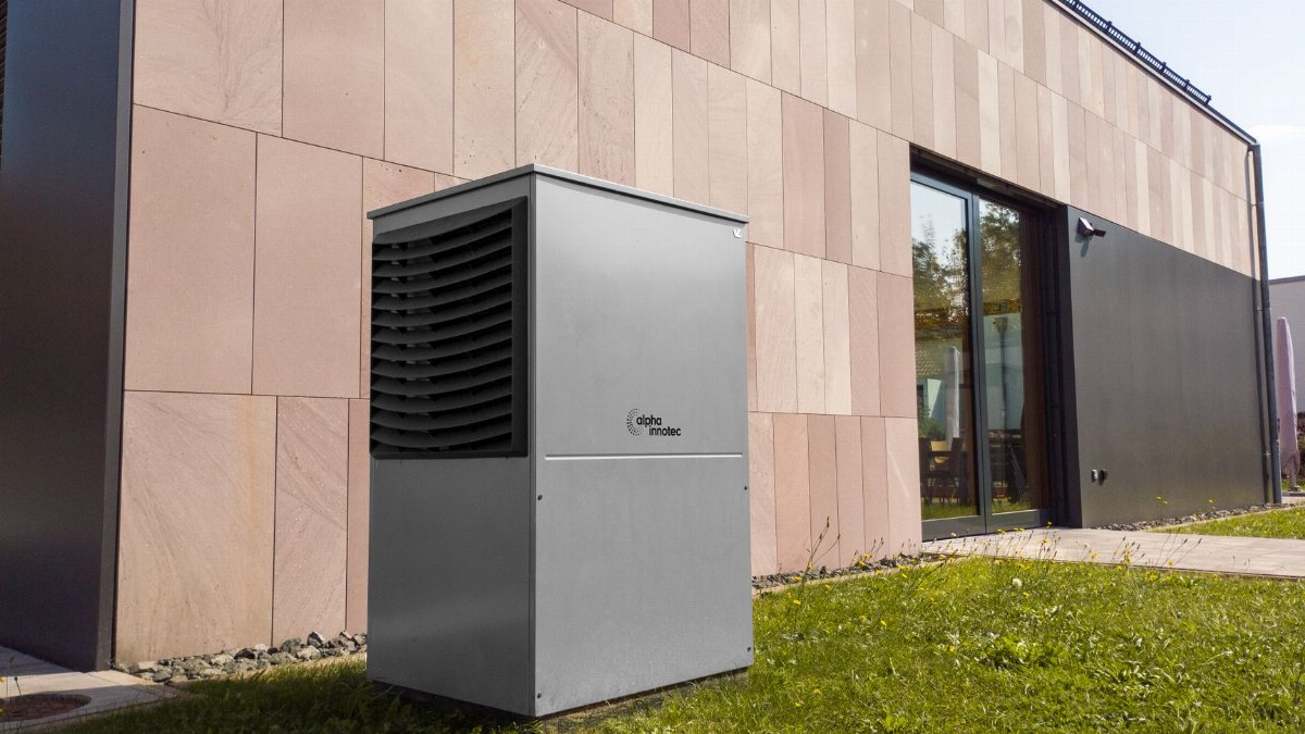 A modern heat pump unit installed outdoors next to a contemporary building, showcasing renewable energy technology.