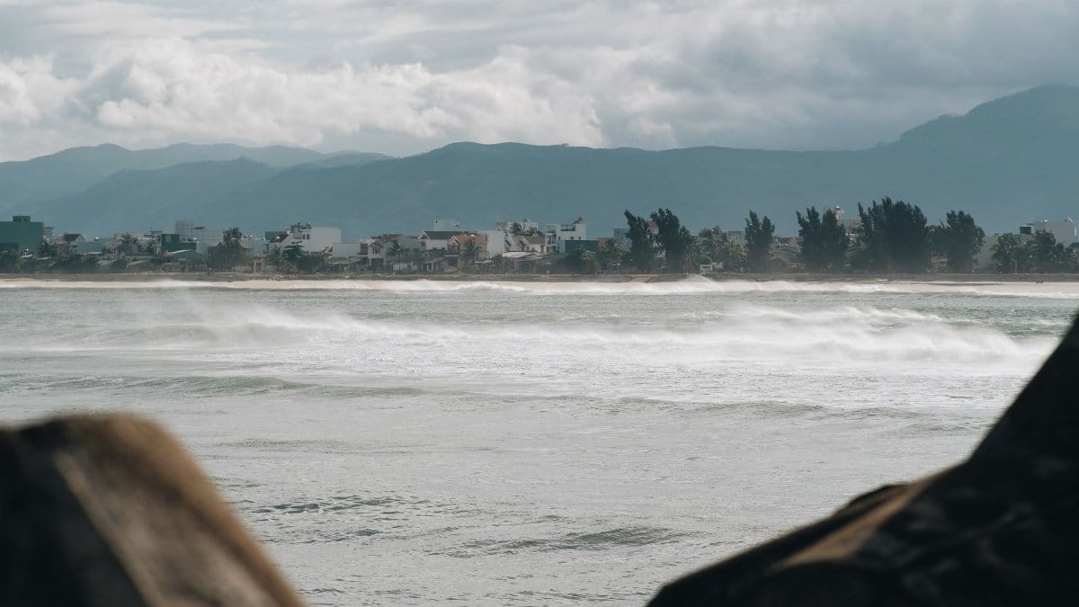 A coastal town with waves crashing against the shore under a stormy sky.