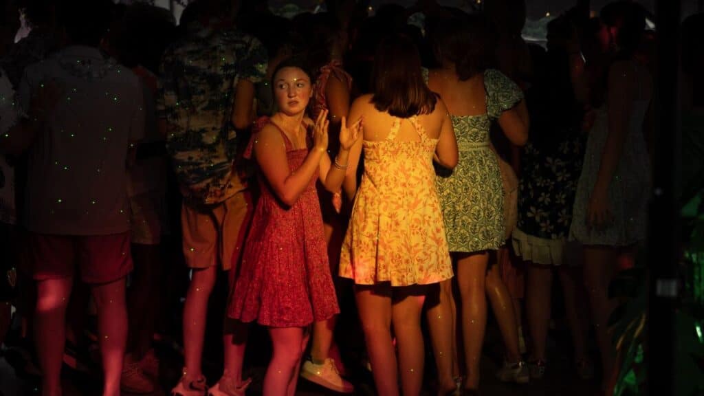 A group of women enjoying a night party in colorful dresses, dancing amidst dim lighting.