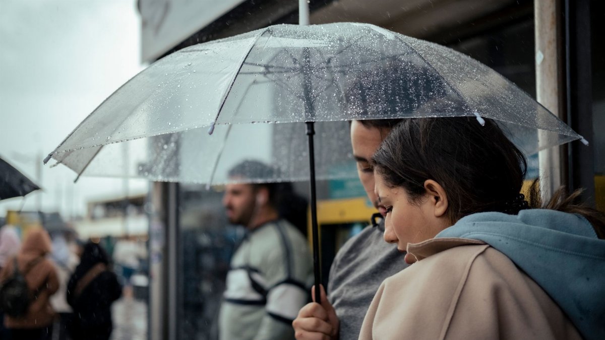 A candid moment of a couple sharing an umbrella in a busy, rainy city street.