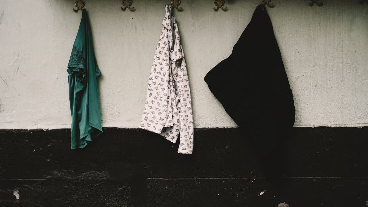 Three pieces of clothing hanging indoors on decorative wall hooks, minimalistic style.