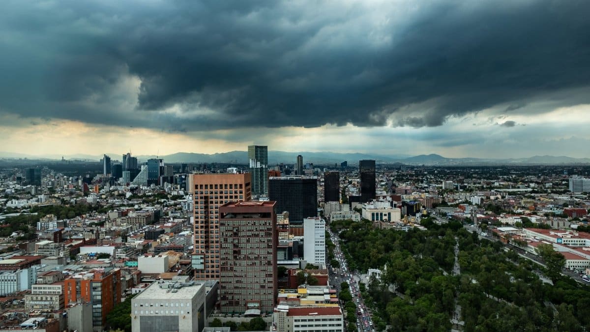 Aerial view of Mexico City's skyline under dark storm clouds, showcasing urban architecture and dramatic weather.