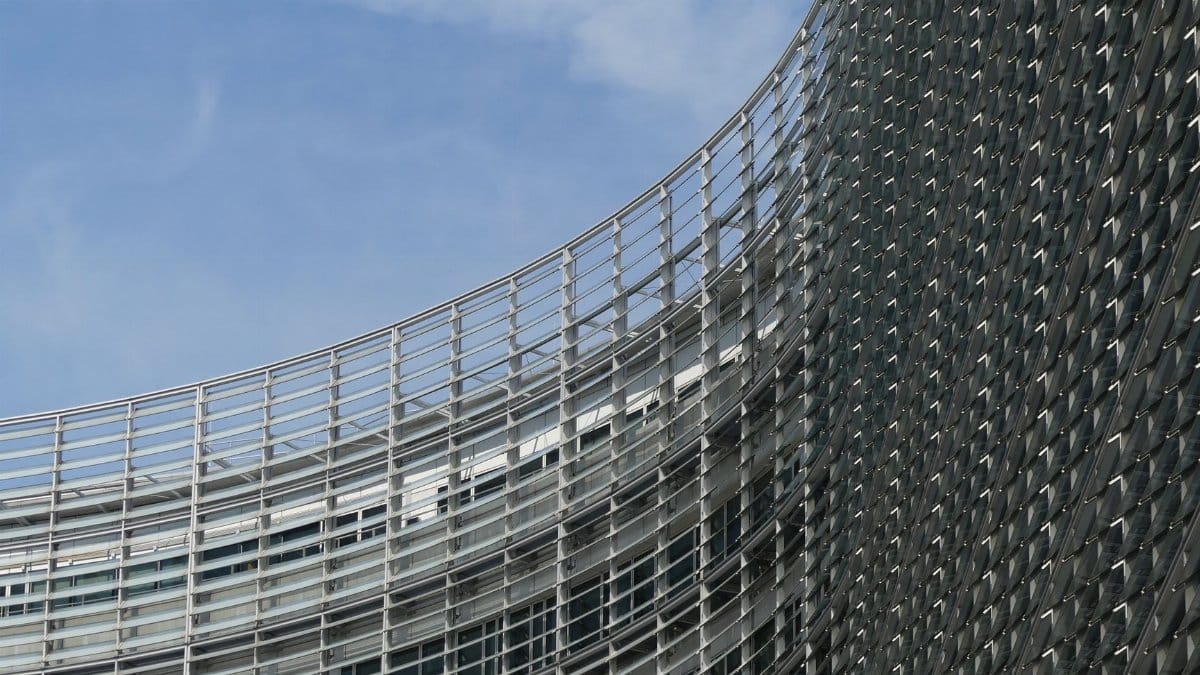 Curved facade of the European Commission building in Brussels under a clear sky.